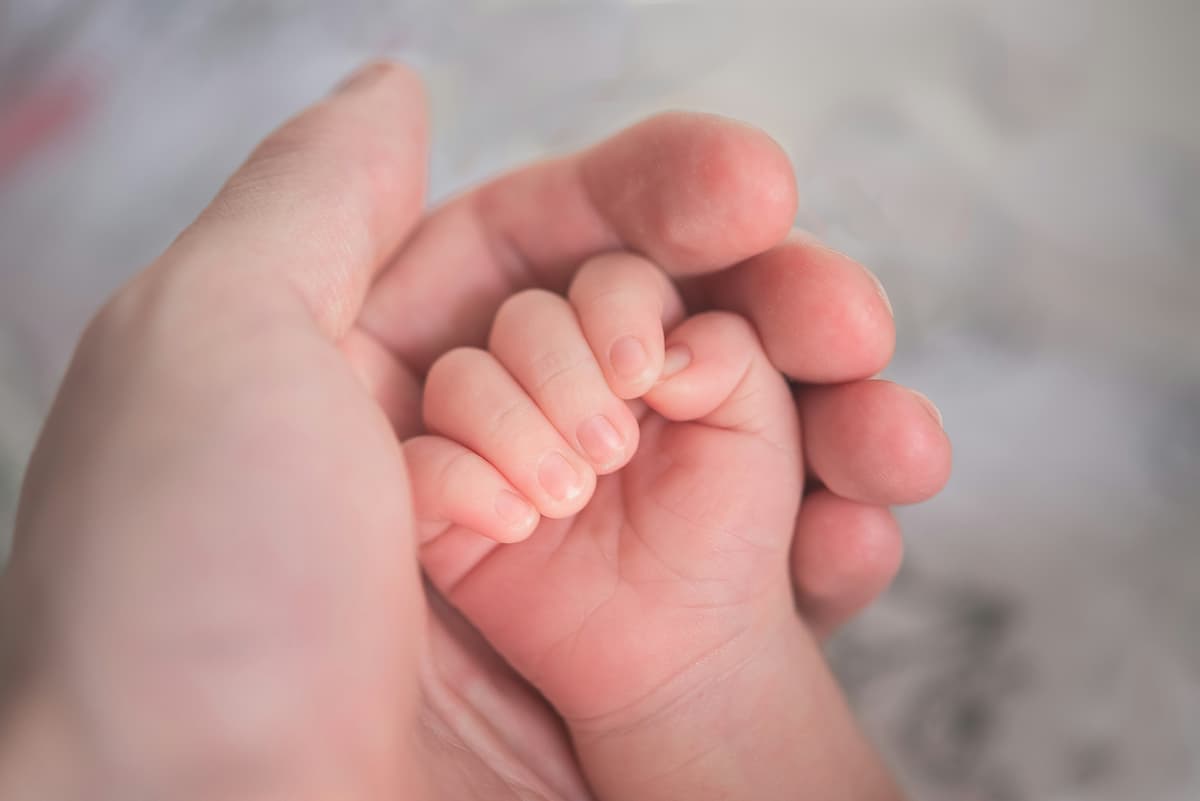A newborn's tiny hand resting in an adult palm.